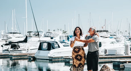 People celebrating along a marina with docked boats in the background.