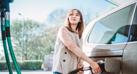 Woman fueling her vehicle at a gas station. 