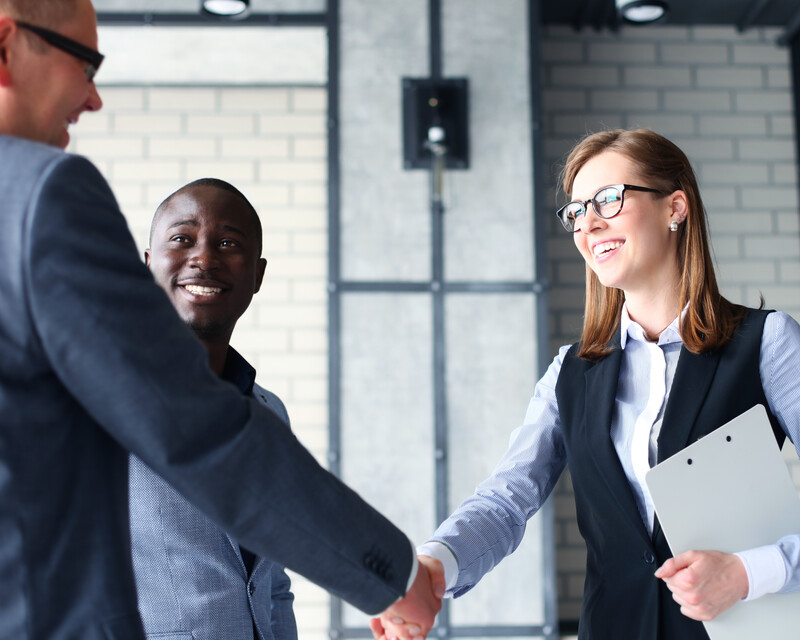 3 people around a table shaking hands to depict Materion's collaboration with customers