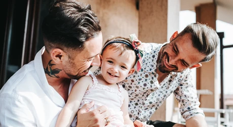 Happy LGBT couple sitting outside with their young daughter 