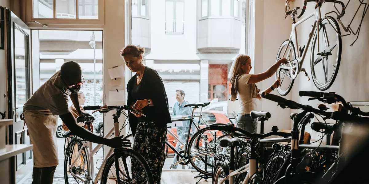 African American business owner in bicycle shop helping customer with bike 