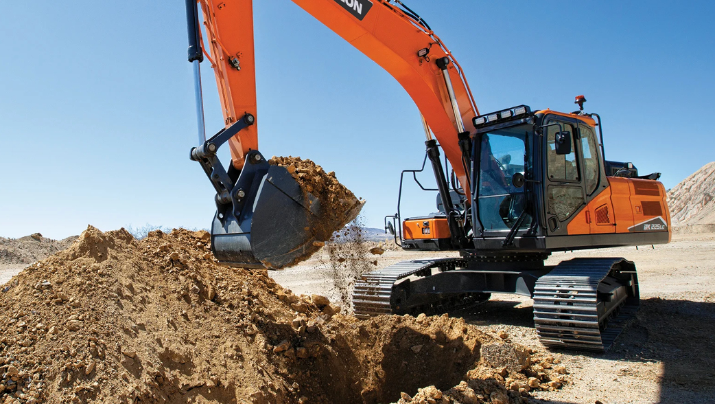 A DEVELON crawler excavator scooping a pile of dirt on a job site.