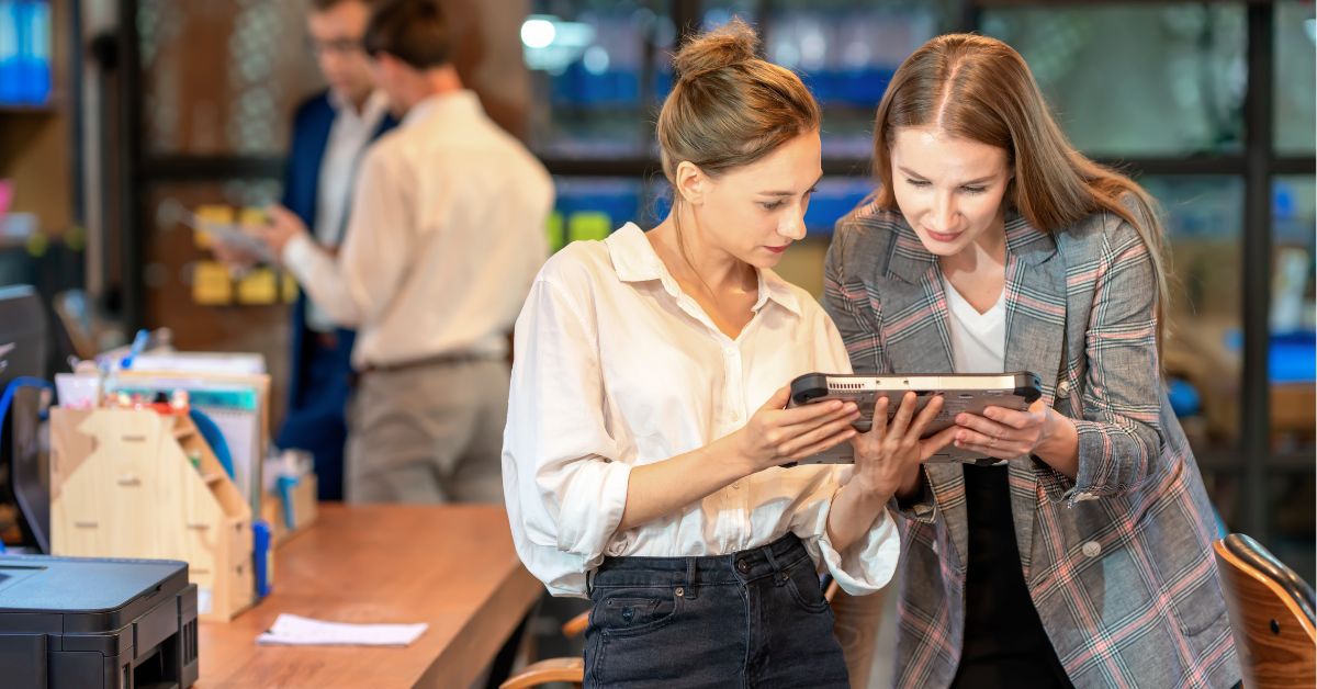 2 women in an office looking at a tablet screen 