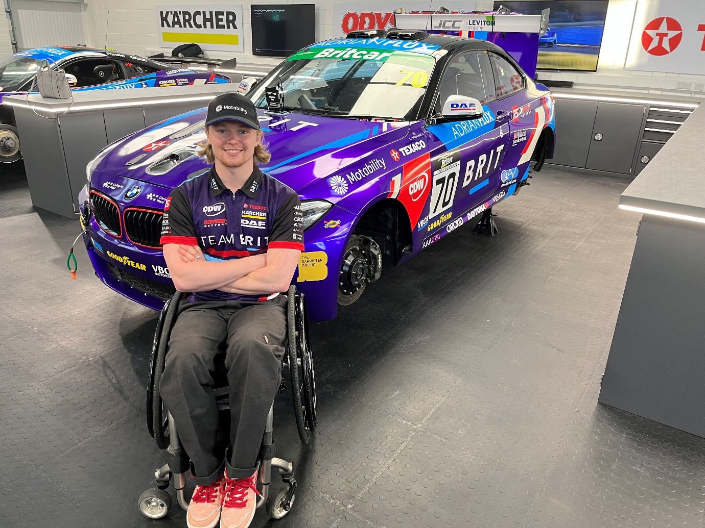 Noah sitting in front of a Team BRIT car