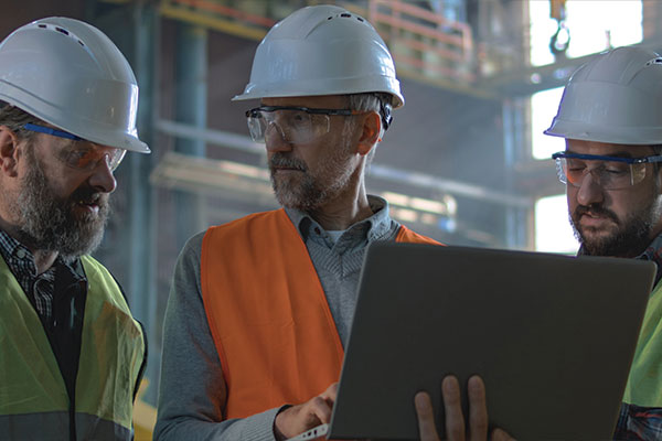 Industrial engineers reviewing technical plans on a laptop