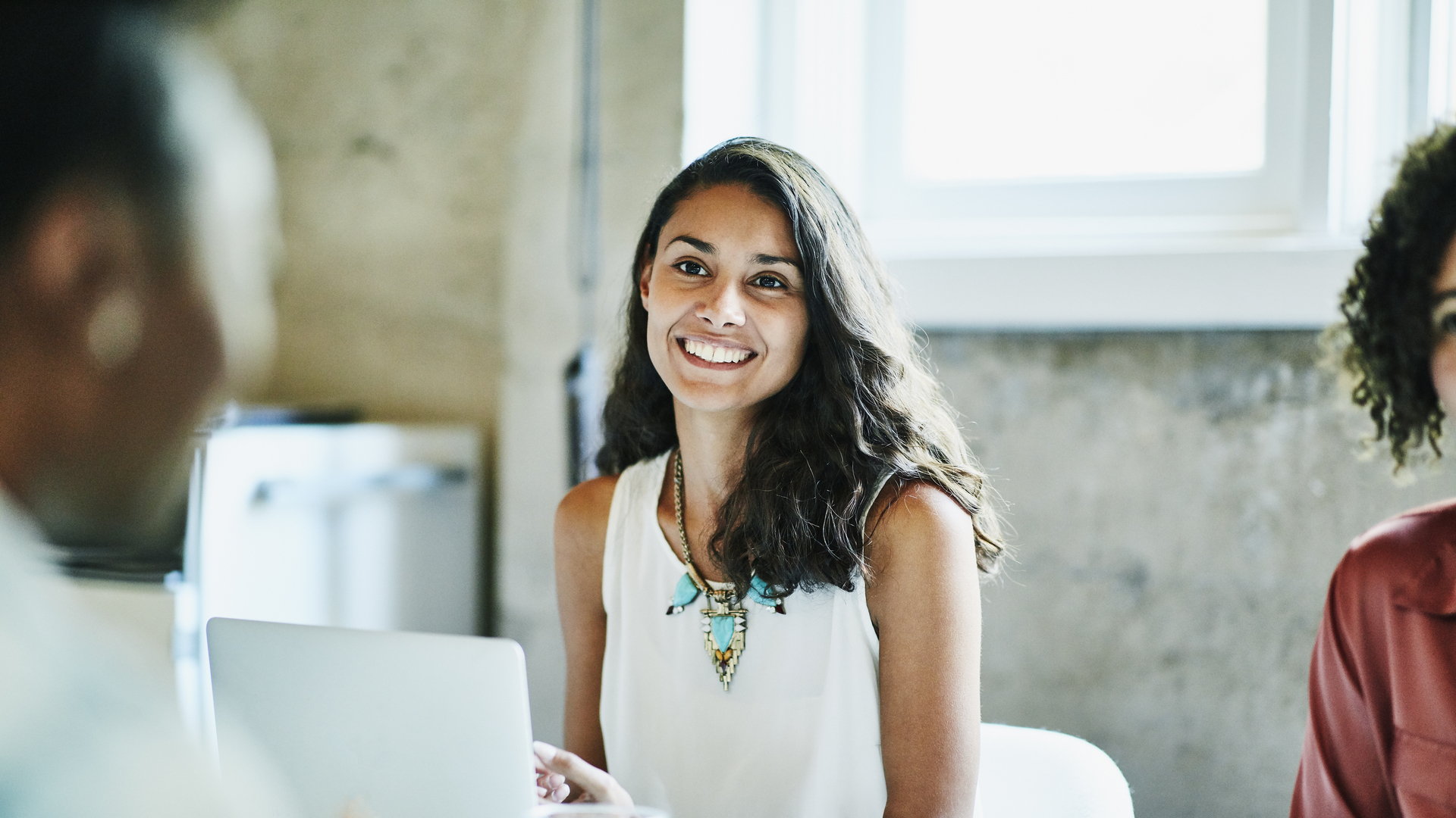 Smiling businesswoman in discussion with colleagues during meeting in office conference room