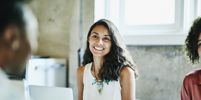 Smiling businesswoman in discussion with colleagues during meeting in office conference room