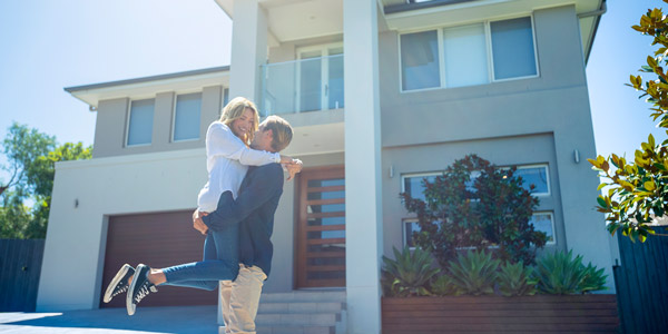 happy couple embracing each other front of their home