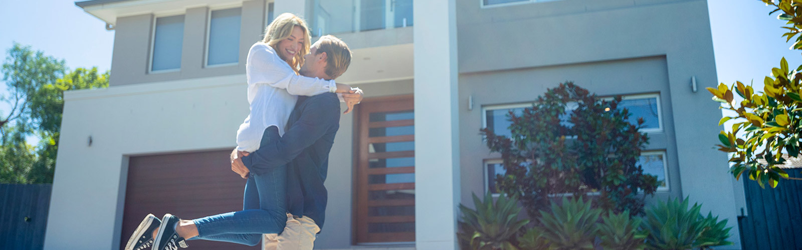 happy couple embracing each other front of their home