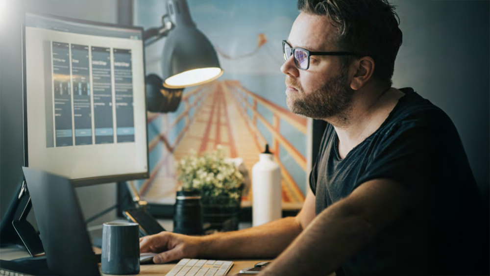 Image taken from Vocus Whitepaper: How to leverage your infrastructure for future-proof progress. Man on desktop computer with lamp on.