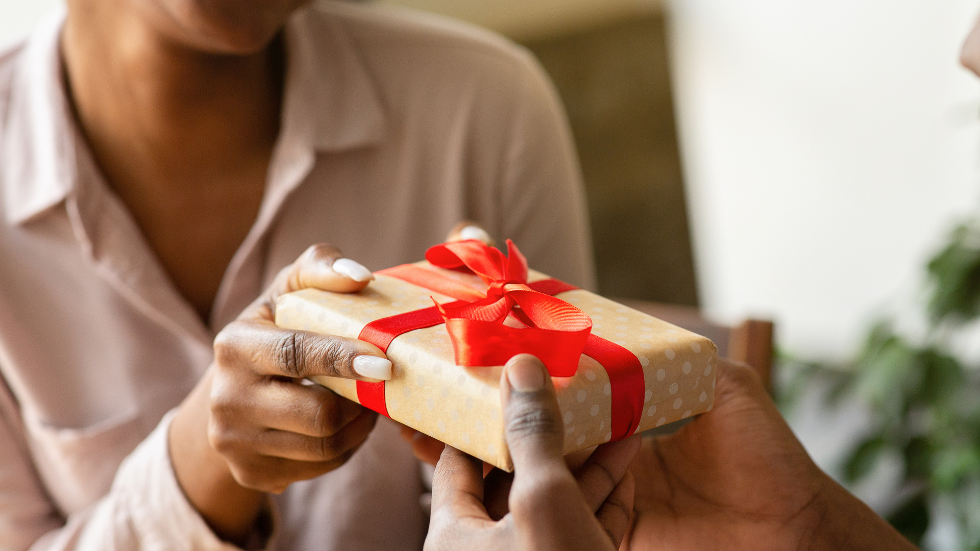 Unrecognizable black guy giving his girlfriend birthday gift at cafe, closeup of hands