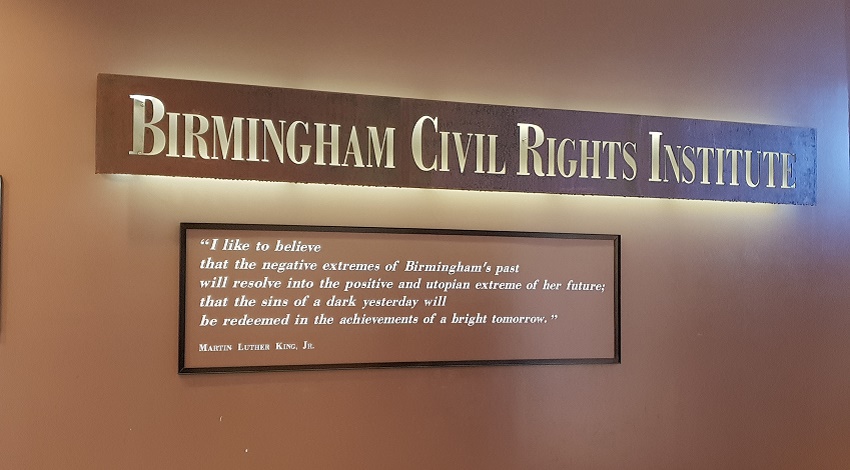 A Martin Luther King, Jr. quote under a sign for the Birmingham Civil Rights Institute, reading "I like to believe that the negative extremes of Birmingham's past will resolve into the positive and utopian extreme of her future; that the sins of a dark yesterday will be redeemed in the achievements of a bright tomorrow."