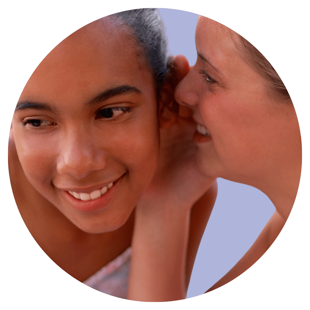 Two people close together, with one leaning towards the other as if speaking quietly inside a circular frame.