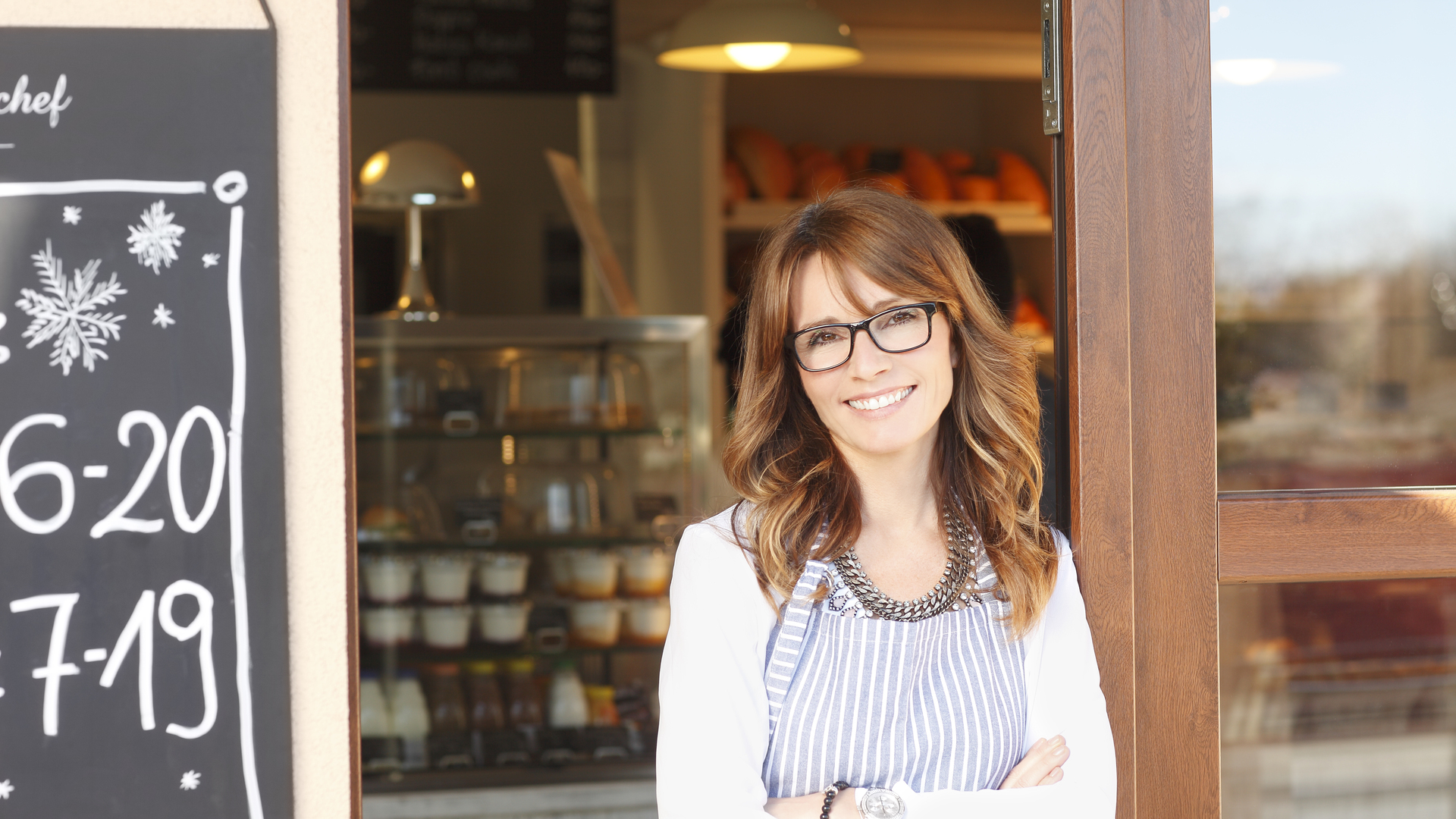 Small coffee shop owner standing in front of store.