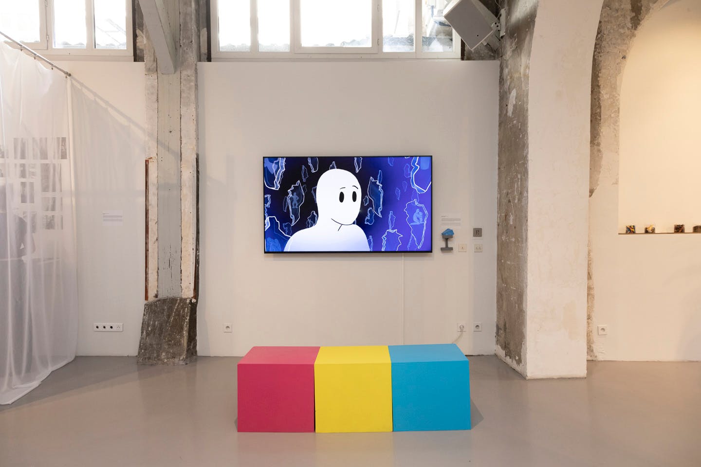 Bright animated character displayed on wall screen with colorful bench