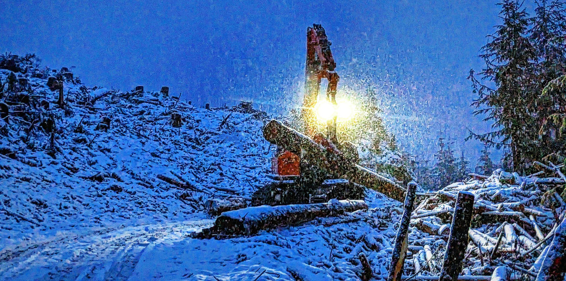 A DEVELON log loader working in a snowy job site.