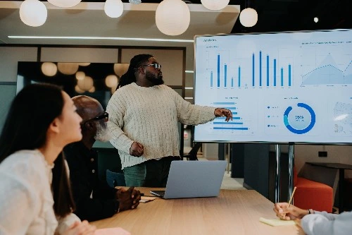 Image of two finance professionals in the services industry looking at graphs on a huge screen