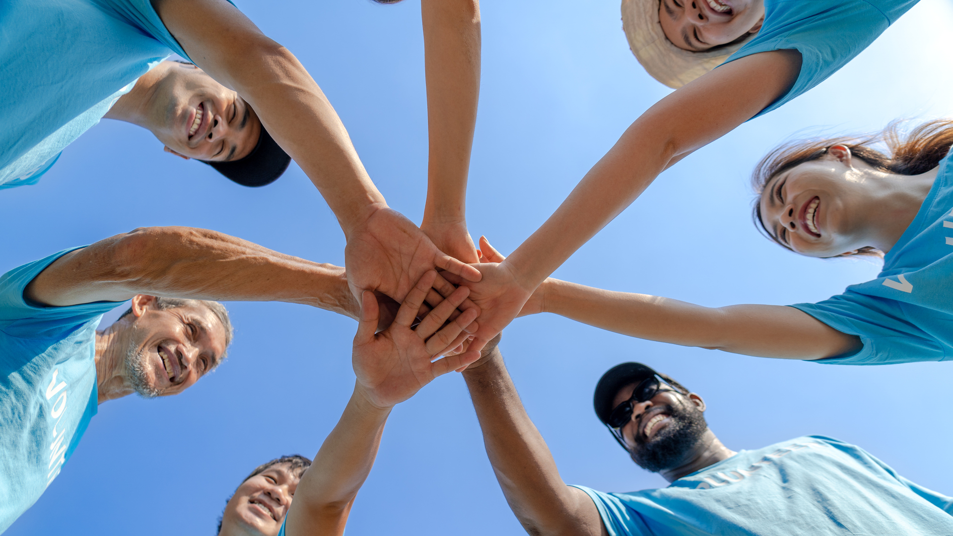 Group of happy diverse volunteers joining stacked hands together