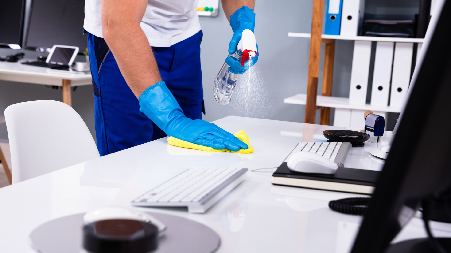 Janitor cleaning white desk in office