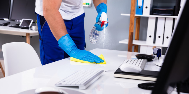 Janitor cleaning white desk in office