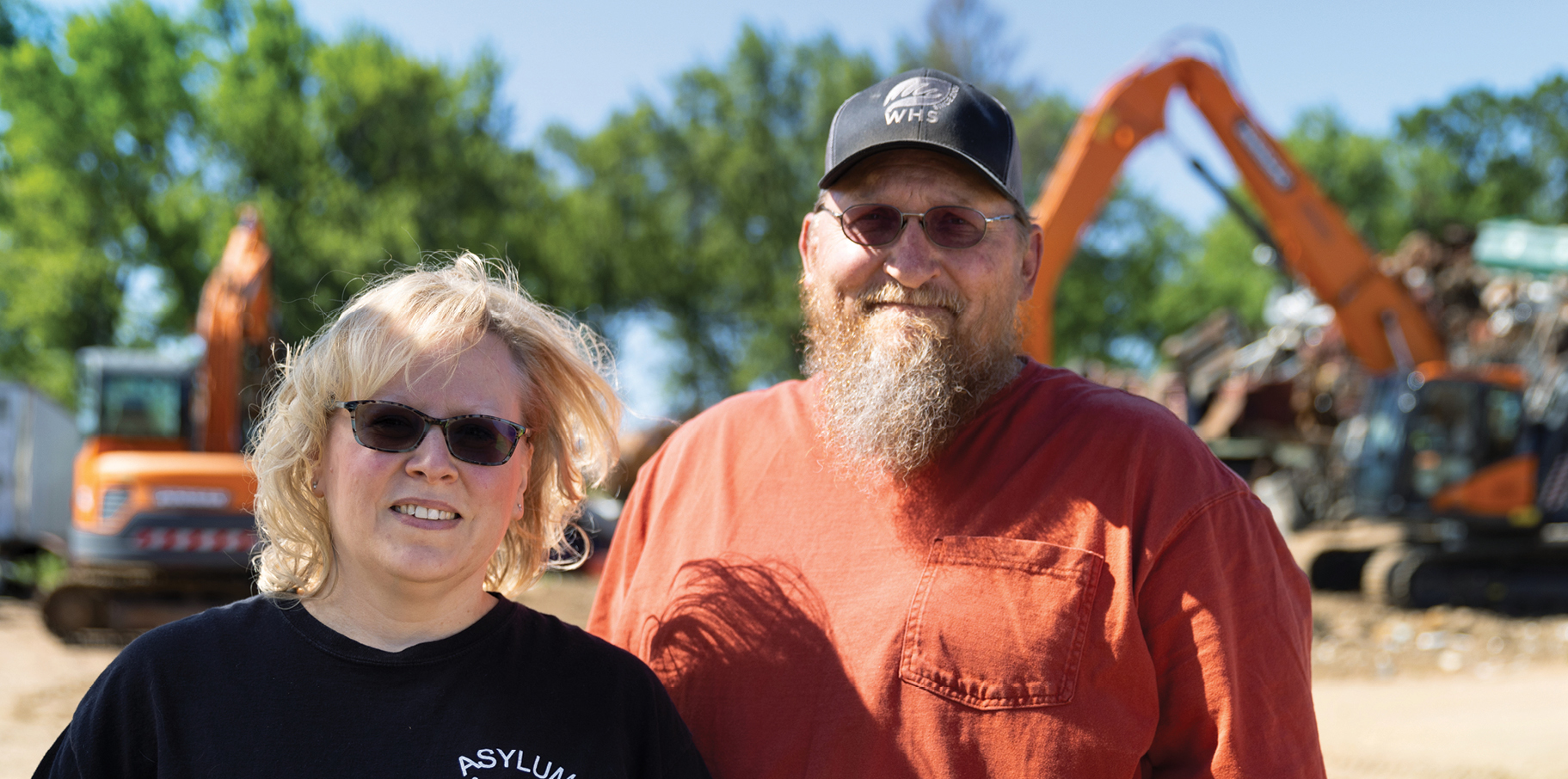 Lisa and Chris Burt of Asylum Scrap Services standing in front of their DEVELON machines.