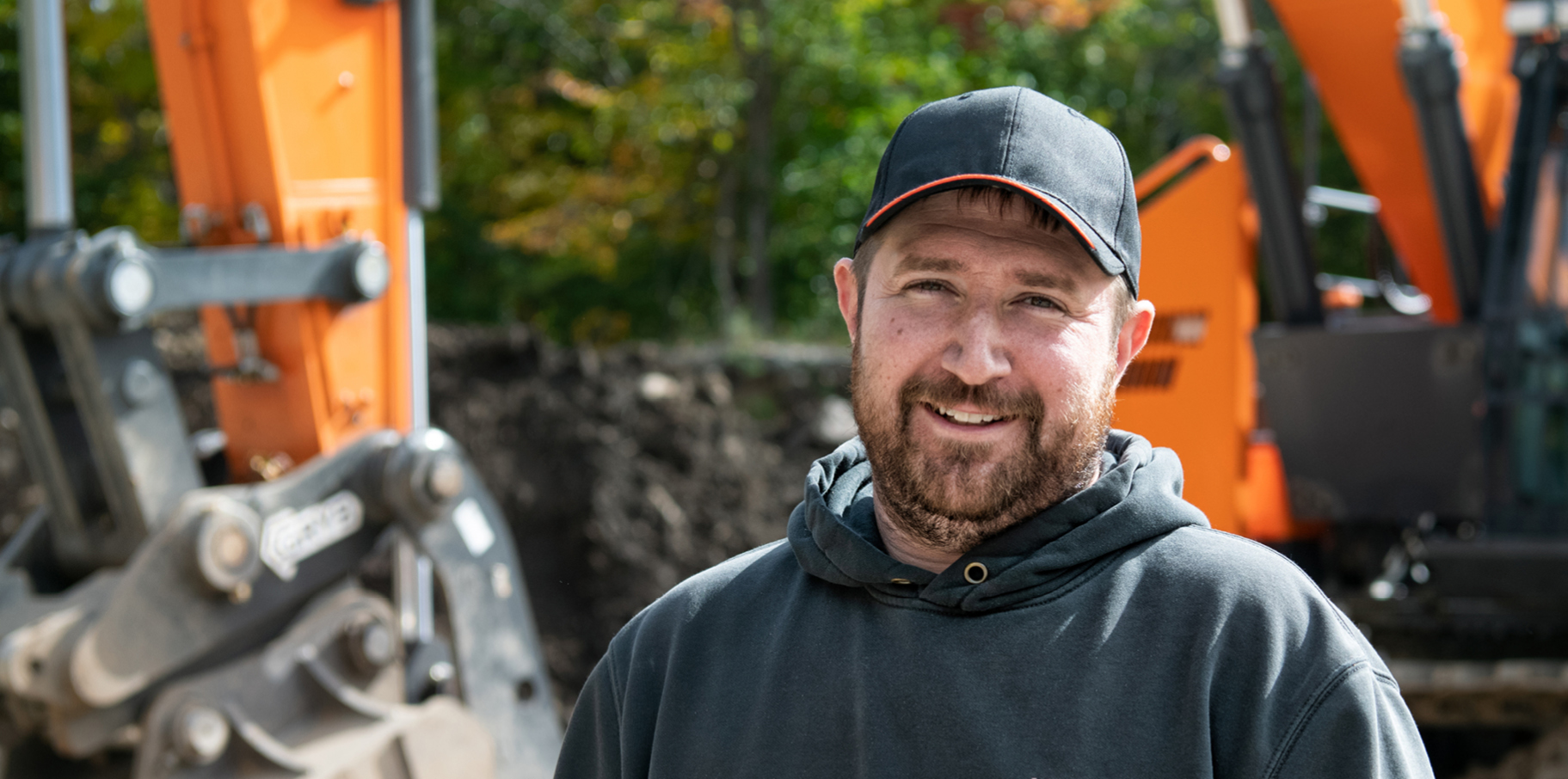 Josh Trudeau of Trudeau Construction standing in front of a DEVELON machine.