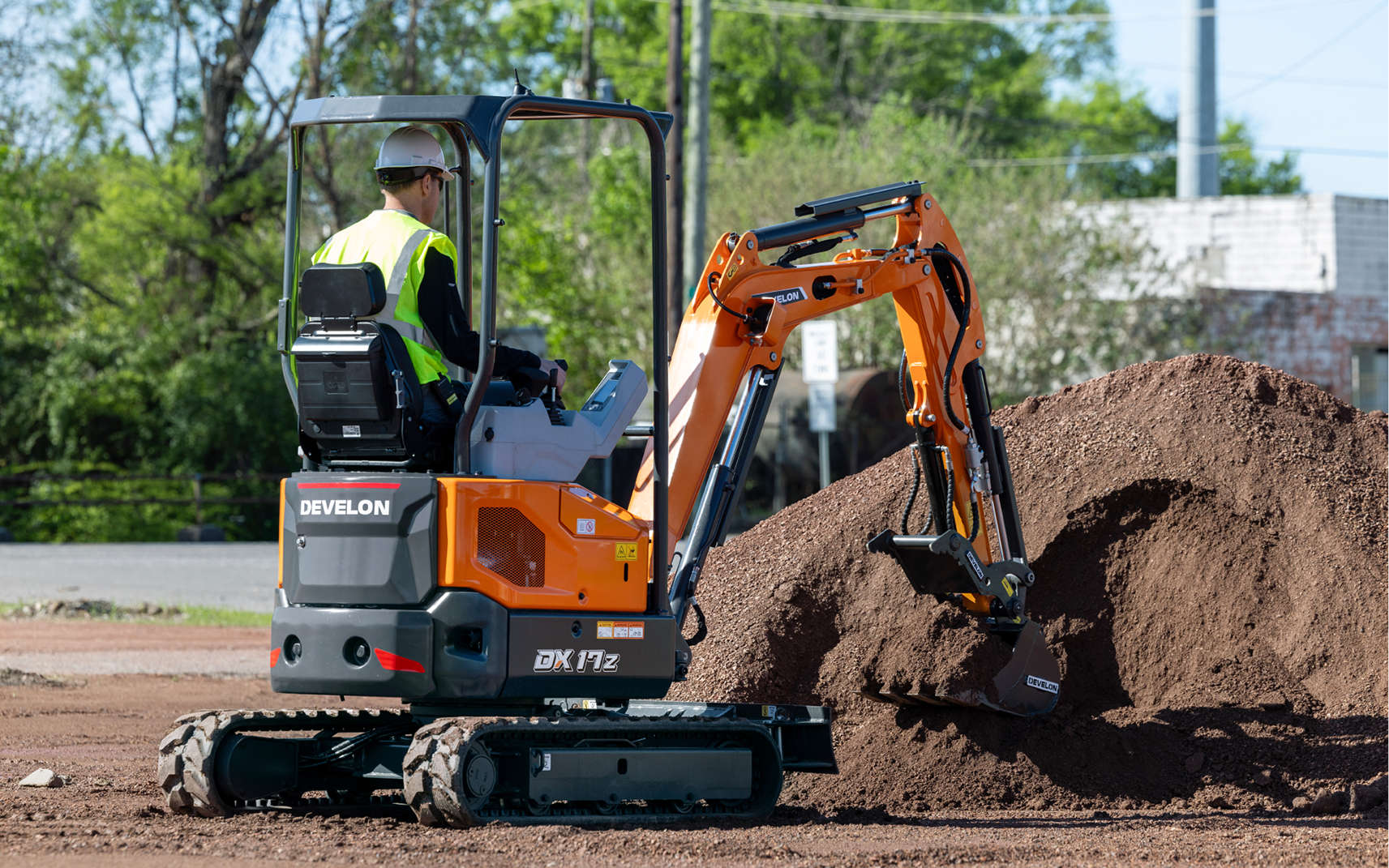 Operator digging a dirt pile with a DEVELON DX17Z-7 mini excavator.