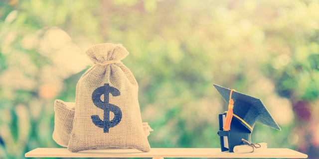 Money cost saving for goal and success in school, education concept : US dollar bills / cash in hessian bags, a black graduation cap or hat, a certificate / diploma and a book on simple balance scale.