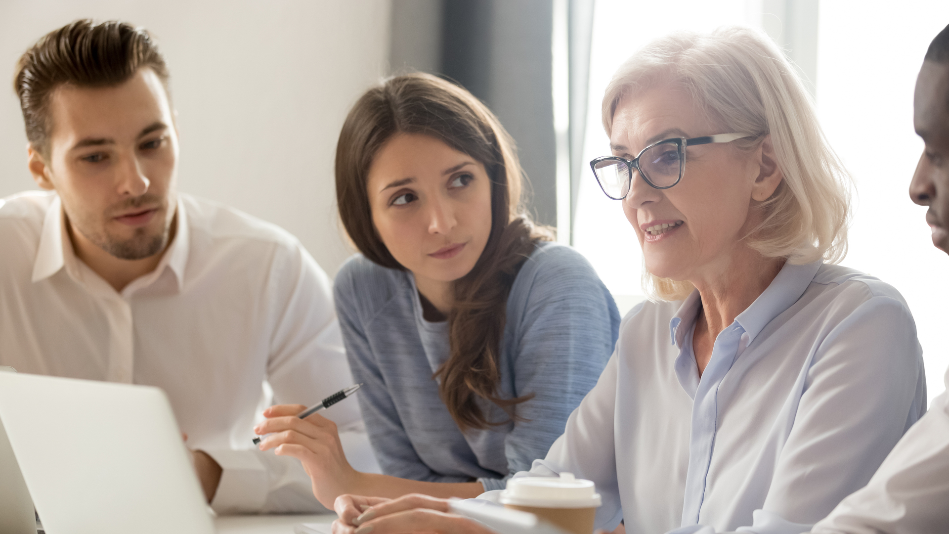 Focused young interns making notes listening to old female manager