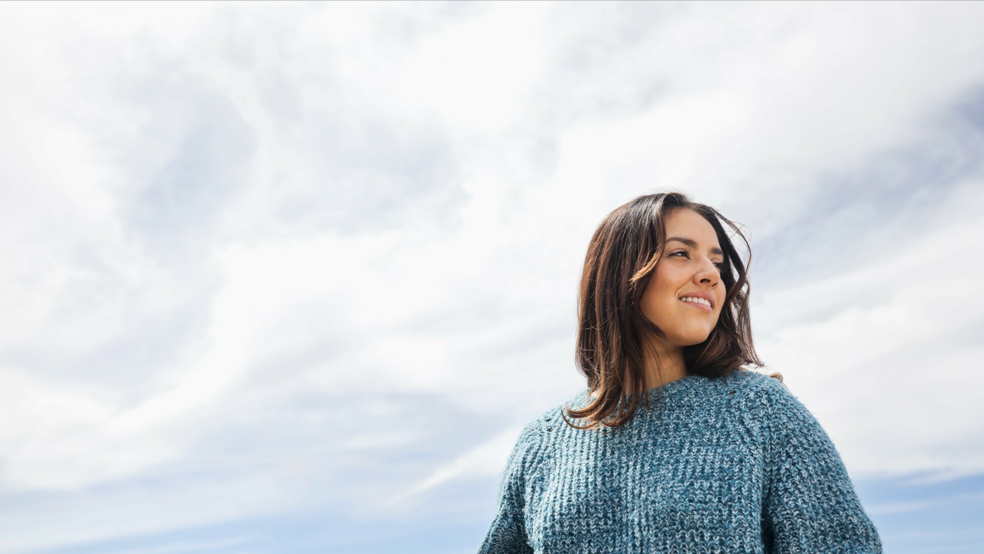Portrait of young woman standing against sky on sunny day