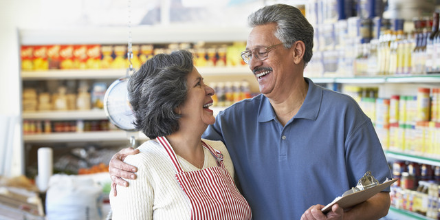 Smiling Hispanic grocery store owners hugging
