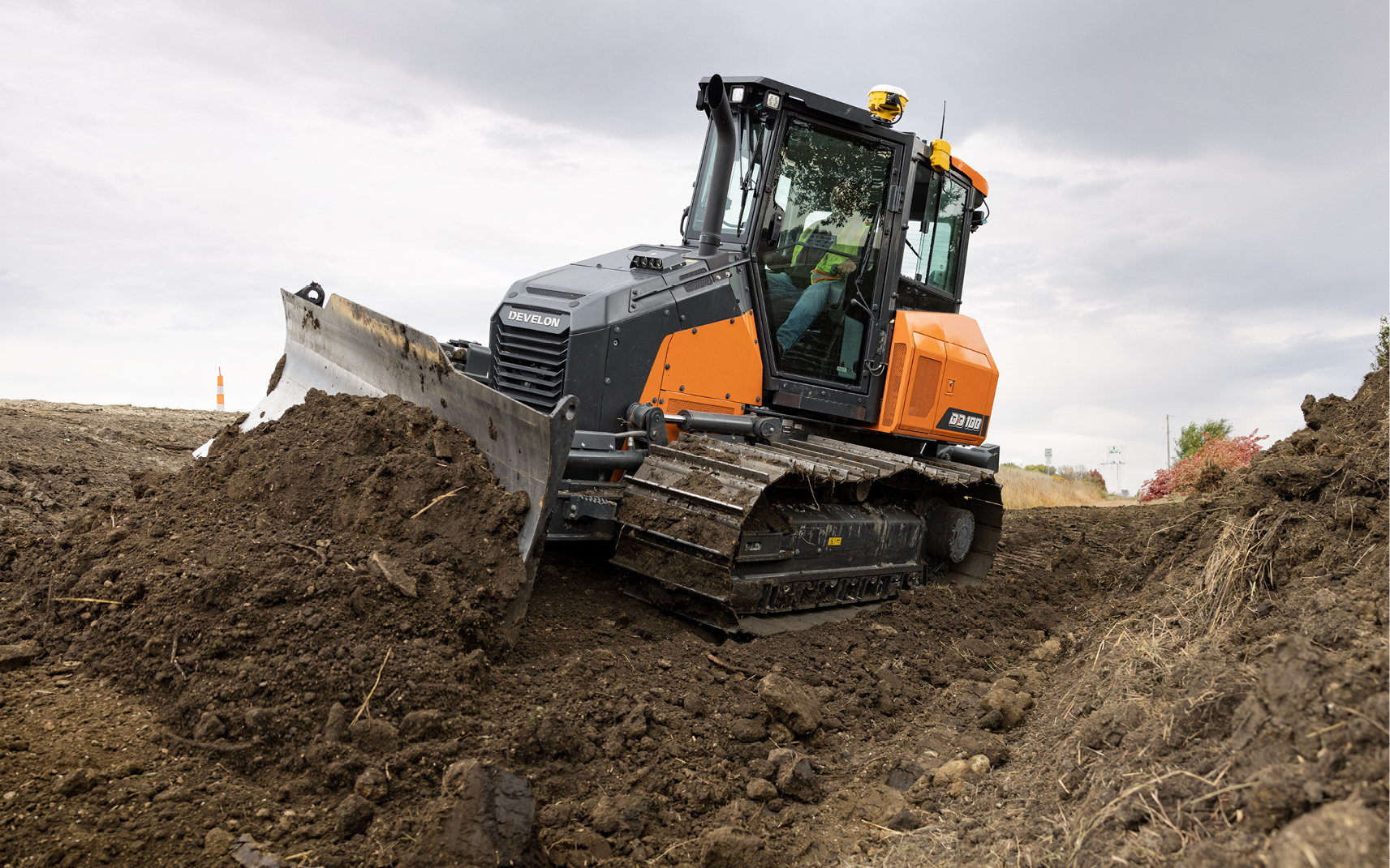 A DEVELON DD100 dozer does 3D grading near a highway.