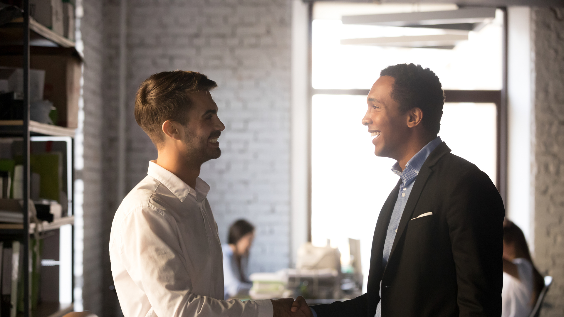 Friendly african and caucasian workers handshaking, welcoming new employee concept