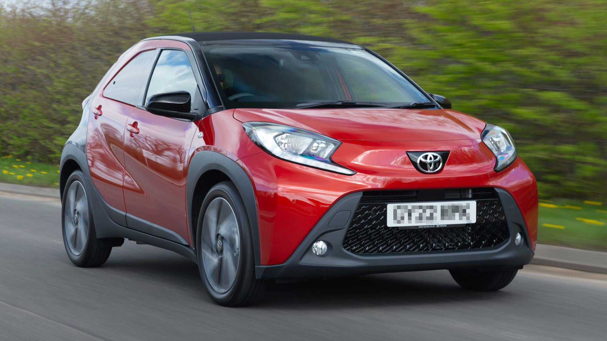 Toyota Aygo X compact crossover driving on urban roads. An ideal city car available on the Motability Scheme