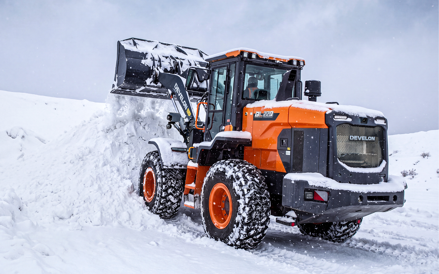 A DEVELON DL250-7P wheel loader dumping a bucket of snow after following a winter prep checklist.