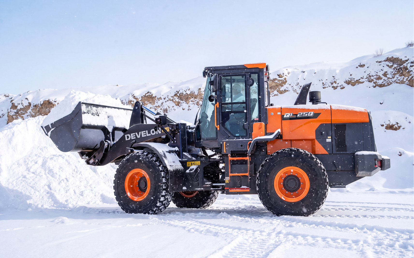A DEVELON DL250-7P wheel loader hauling a bucket of snow after proper winter prep.