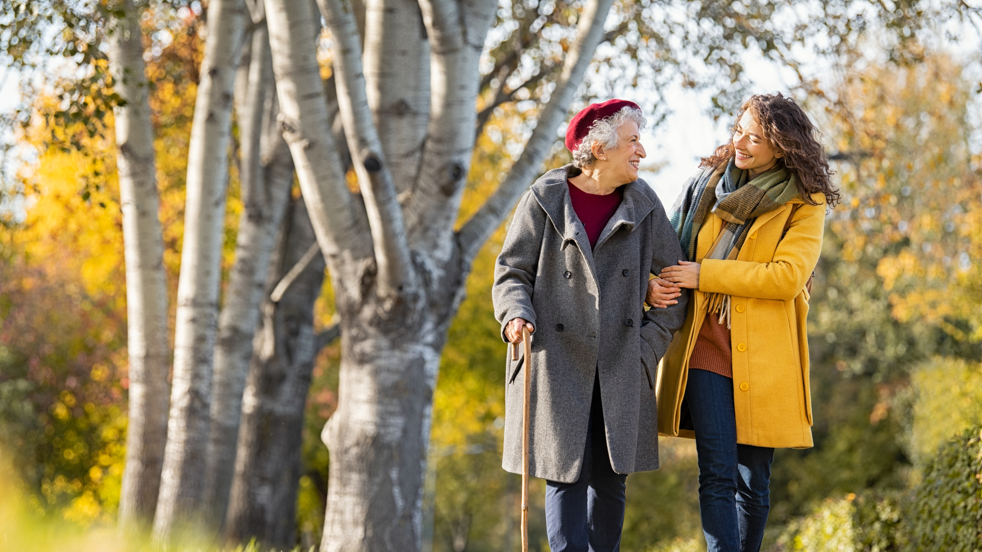 Woman with grandmother walking in park in autumn