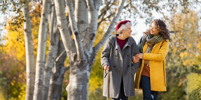 Woman with grandmother walking in park in autumn