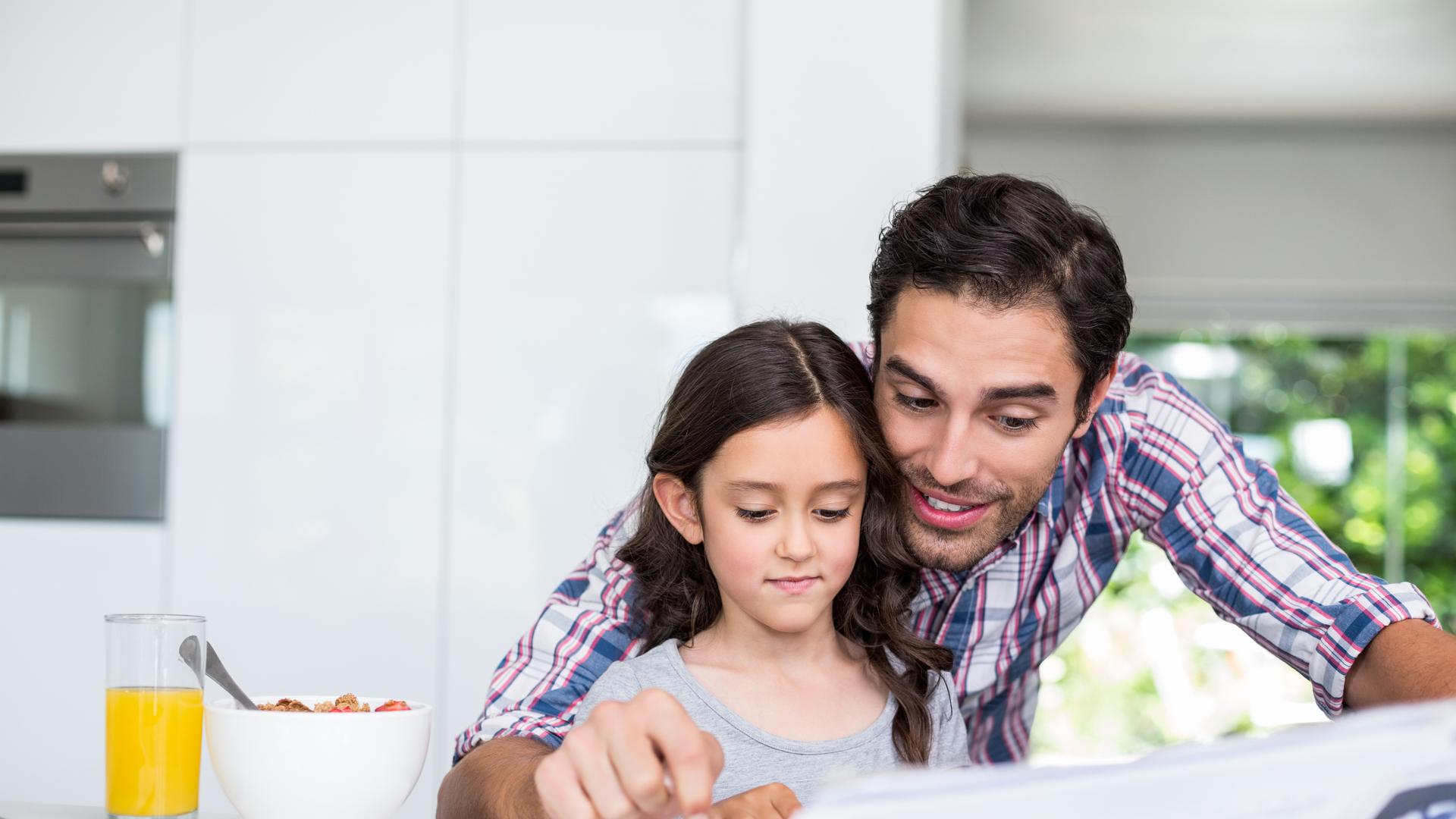 Father and daughter reading newspaper at home