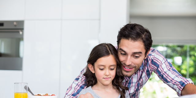 Father and daughter reading newspaper at home