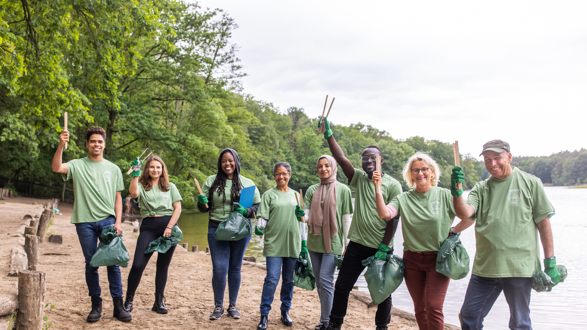 Portrait of happy volunteers cleaning the lakeside