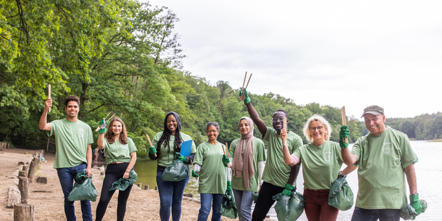 Portrait of happy volunteers cleaning the lakeside