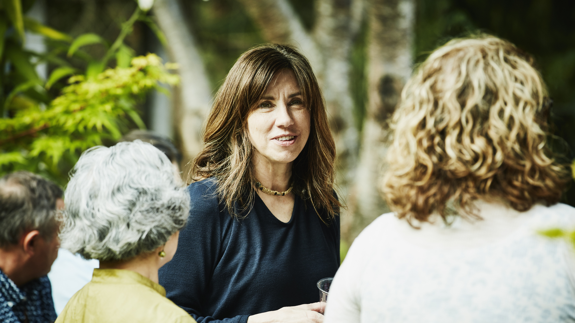 Smiling woman hanging out with friends during summer garden party