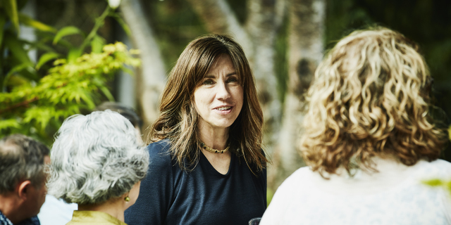 Smiling woman hanging out with friends during summer garden party