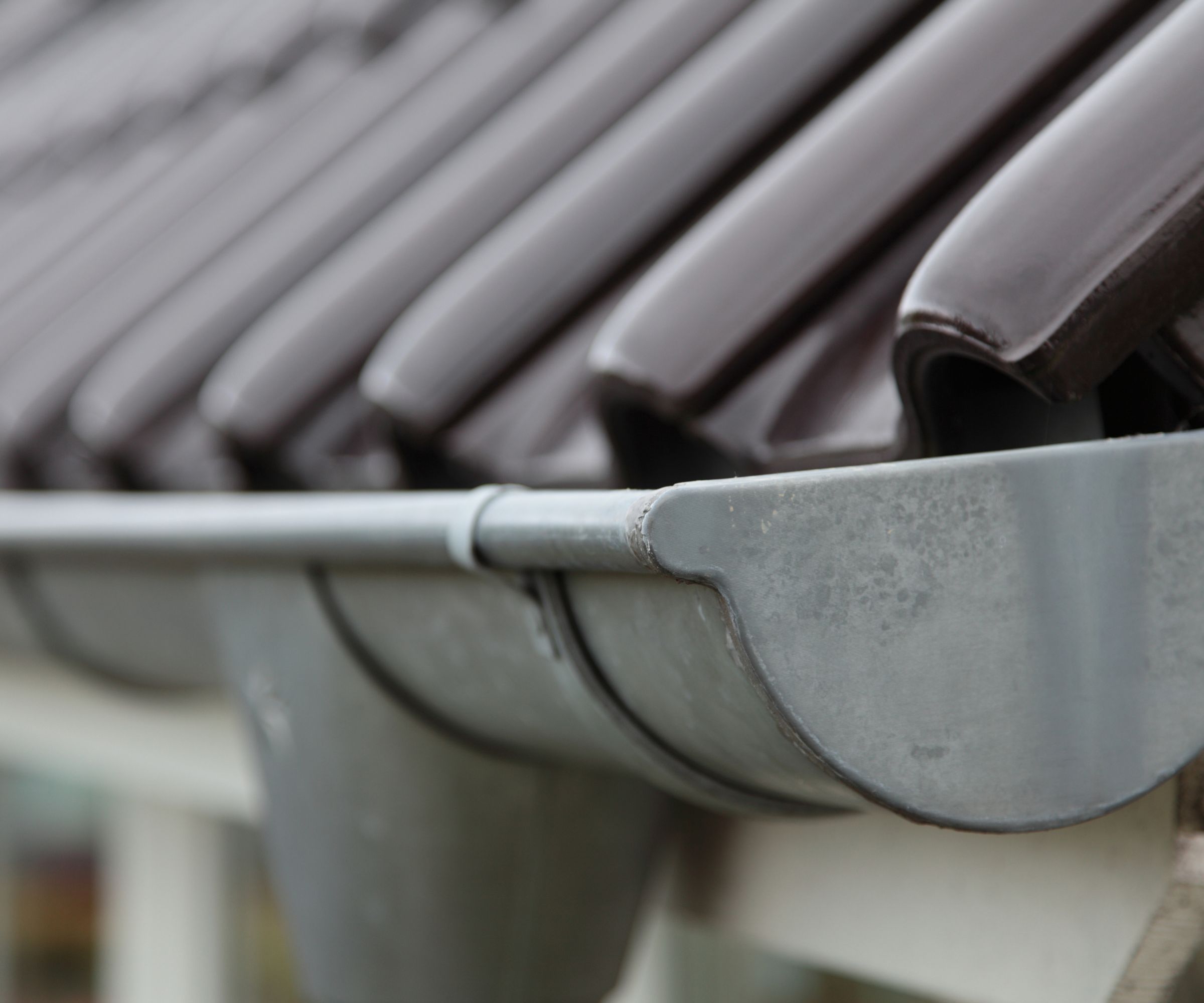 A gray gutter track along the edge of a gray tiled roof.