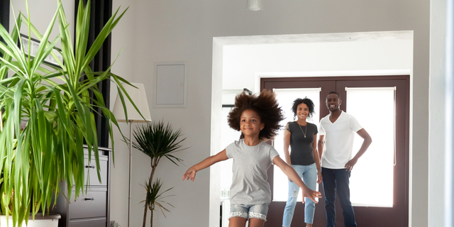 Excited little funny african girl running exploring big modern house on moving day