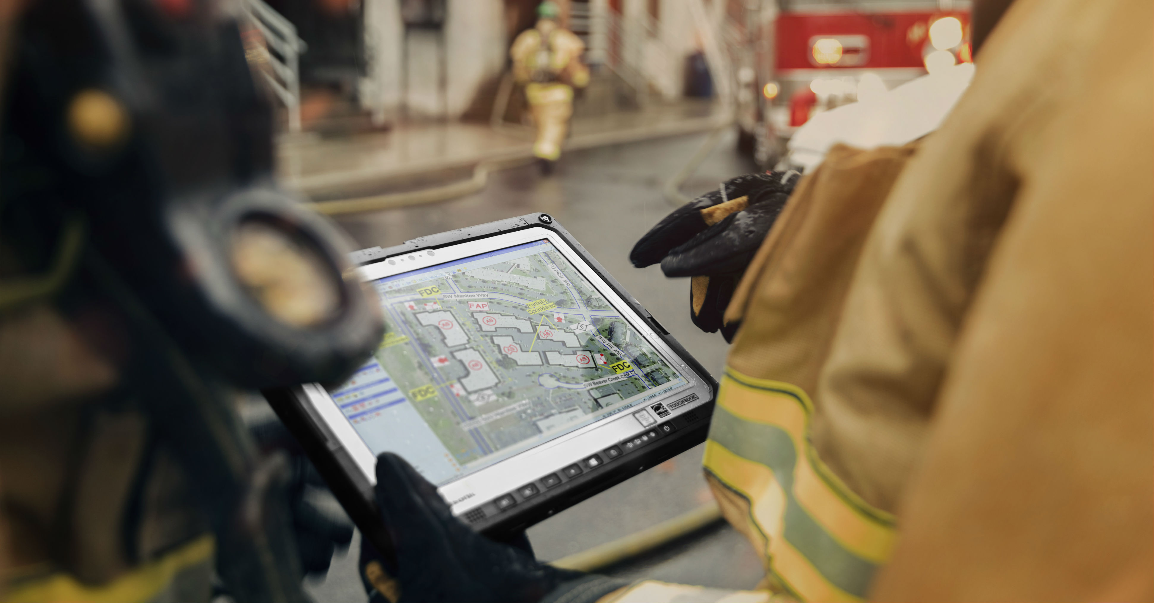 An emergency worker a rugged laptop as part of their firefighter gear