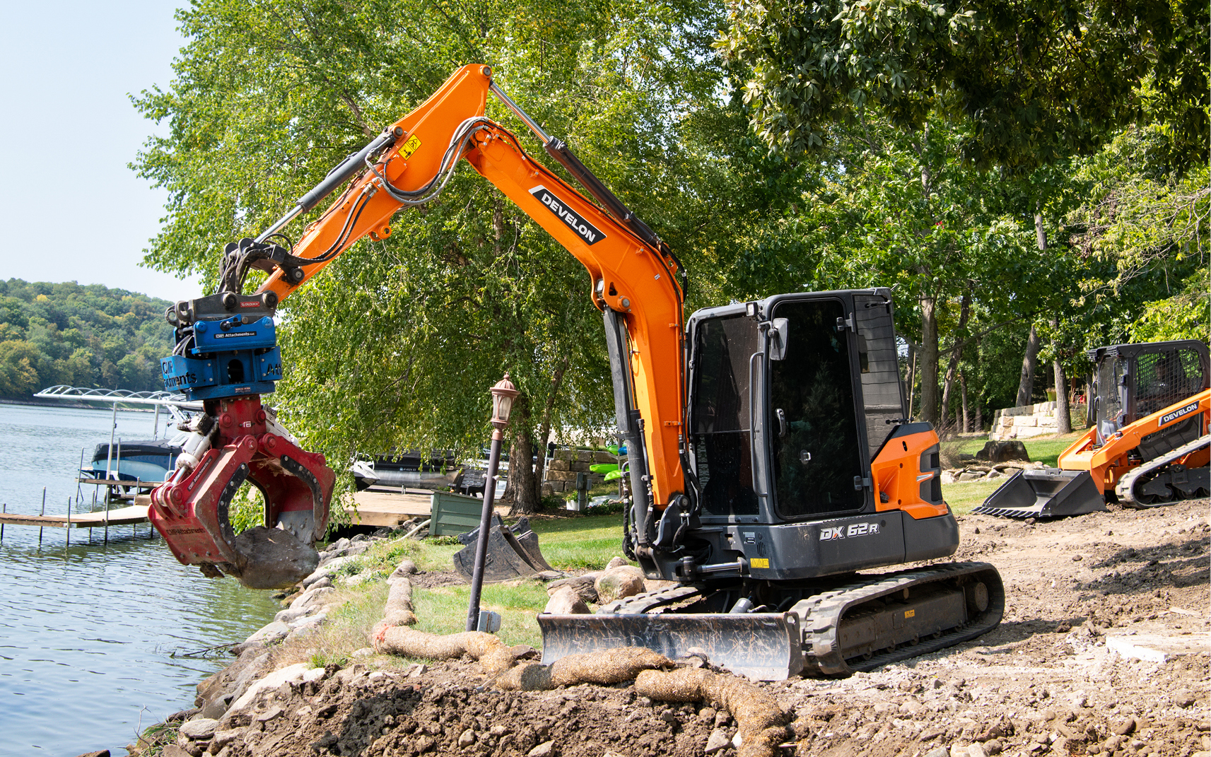 DEVELON mini compact excavator picking up rocks on a landscaping job site. 