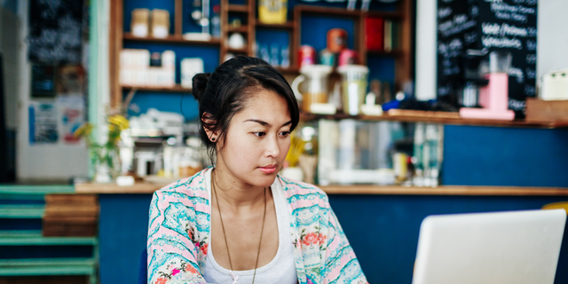 Young Woman Working On Laptop In Colourful Coffee Shop