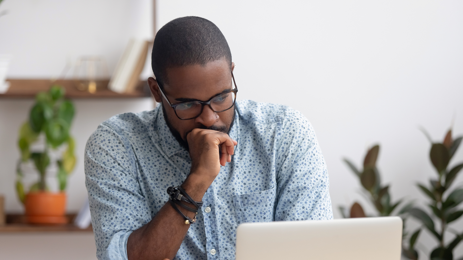 Head shot serious puzzled African American businessman looking at laptop